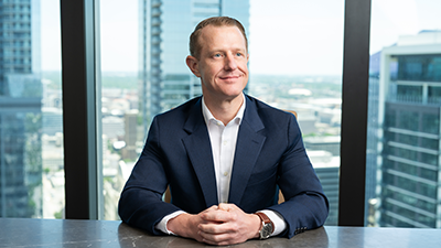Clark Menkes sitting at a conference table in the Austin office in front of a window